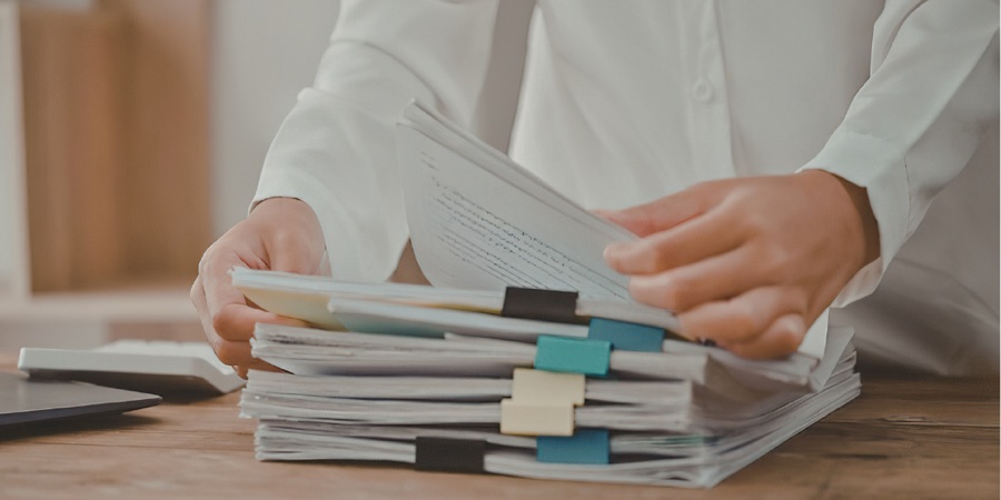 Hands sorting through a stack of tabbed registration paperwork on a desk